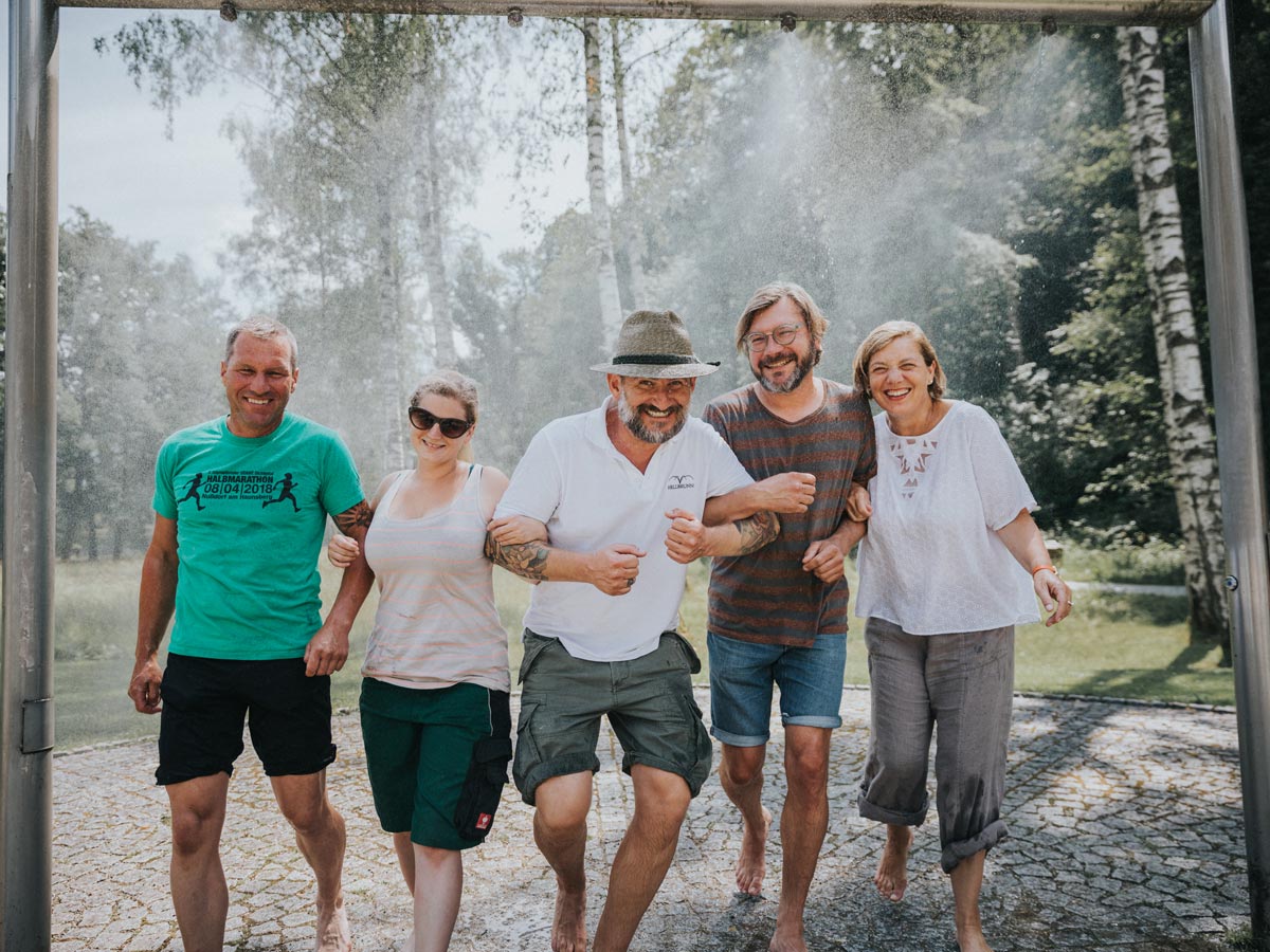 Fünf Personen werden von einer Wasseranlage bespritzt zum abkühlen