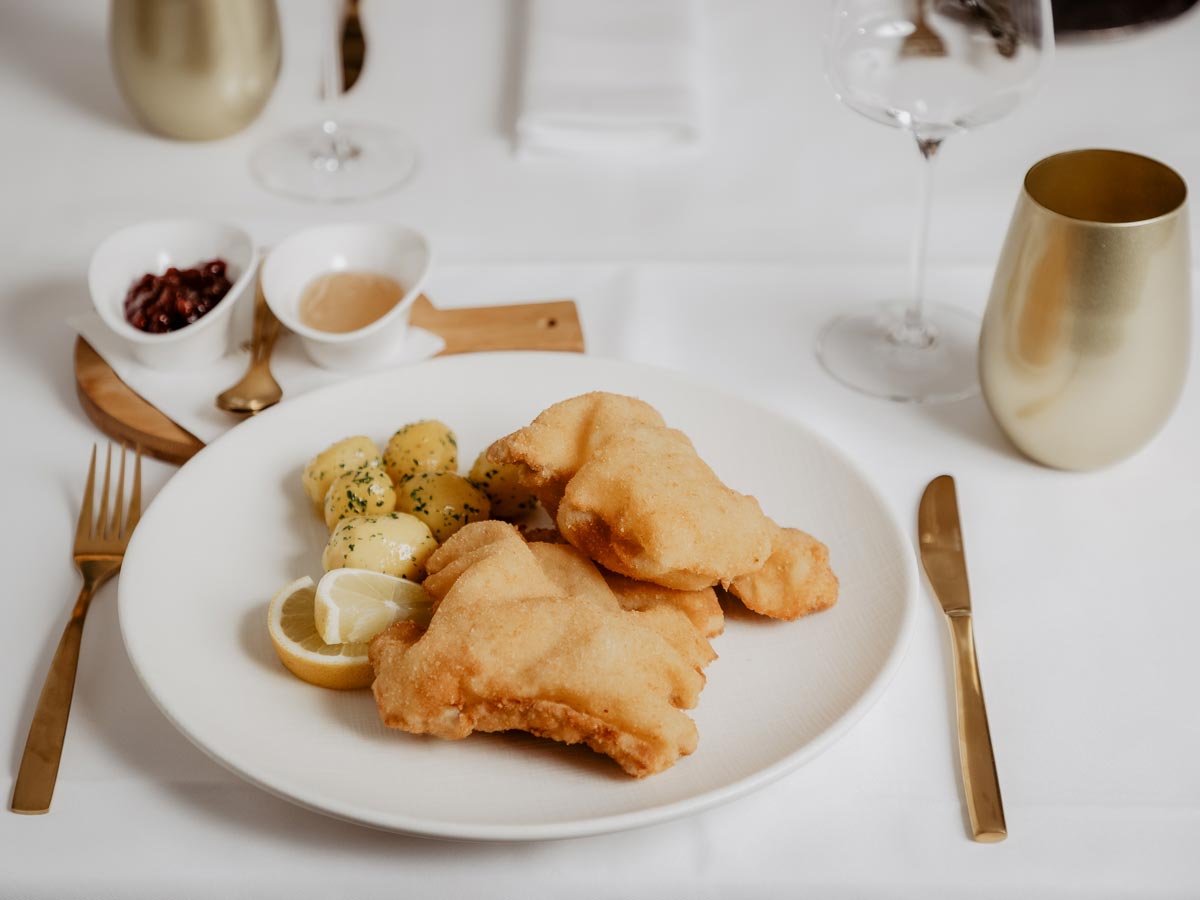 Luftiges Wienerschnitzel auf einem Tisch mit weißer Tischdecke