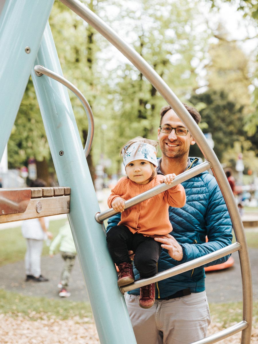 Vater mit seinem Kind an einem Gerüst bei einem Spielplatz